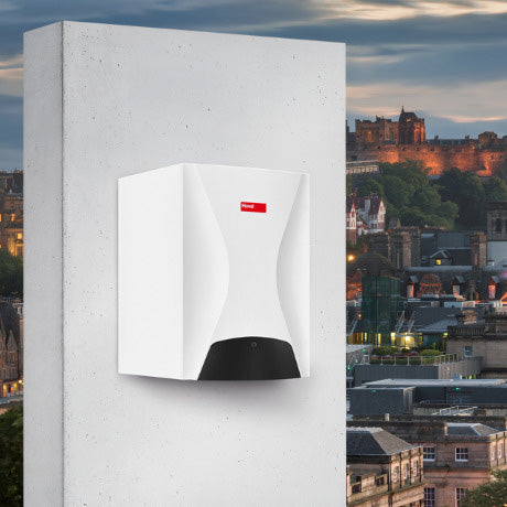 White Hoval compact boiler unit with black accents mounted on a wall set against a backdrop of a city